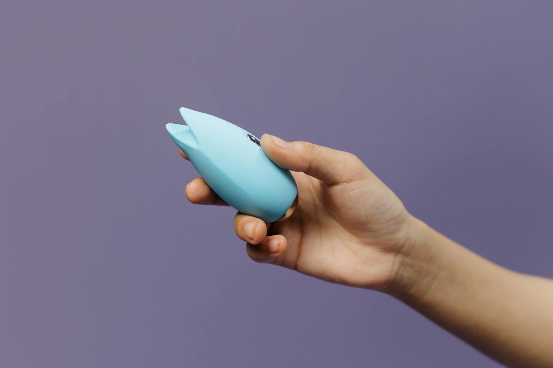 Close-up of hands holding a blue personal massager, representing intimate reconnection and self-discovery