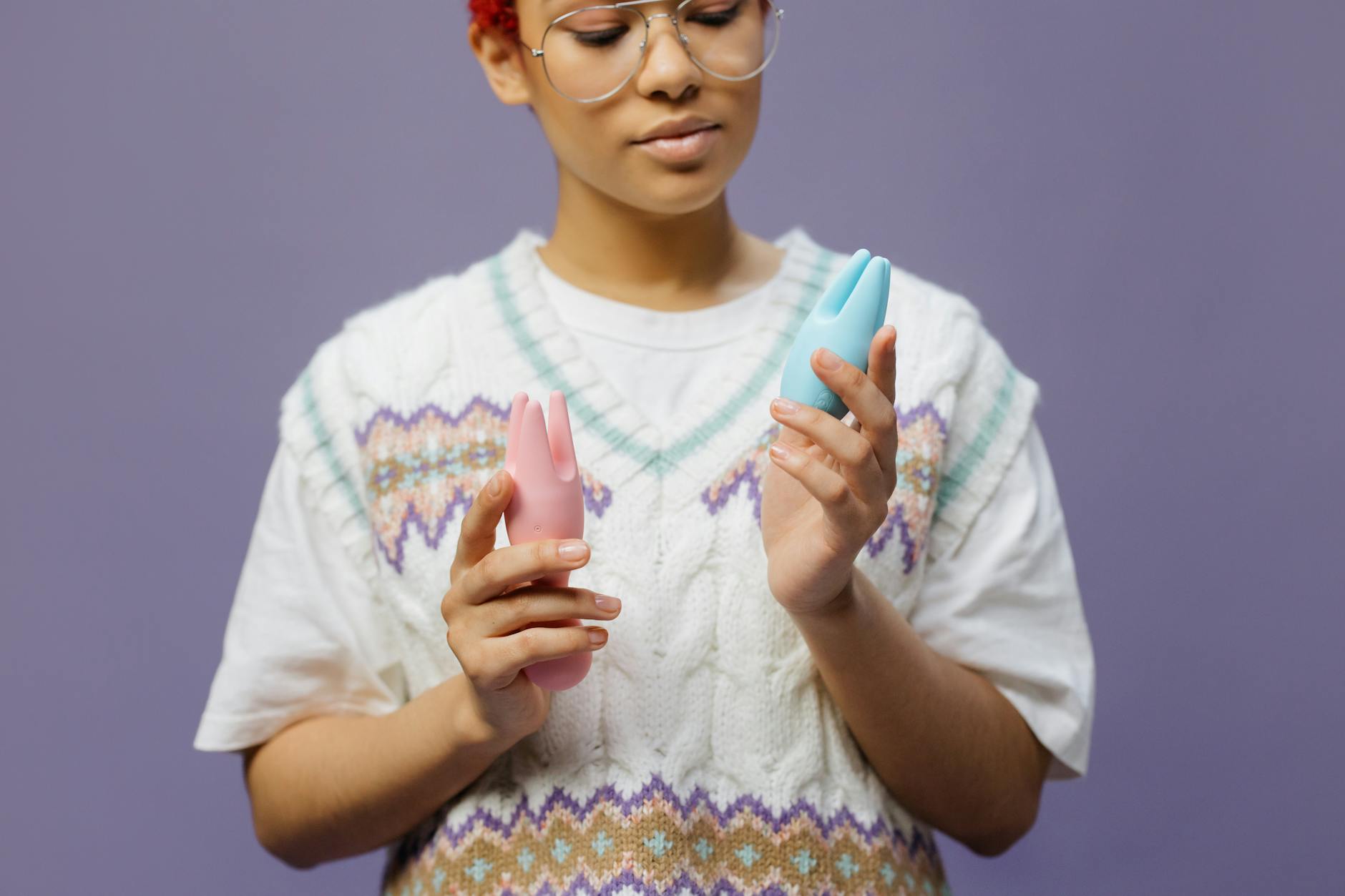 Woman holding colorful clitoral vibrators, representing personal pleasure and cycle awareness